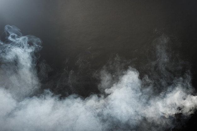 Photo bouffées denses et moelleuses de fumée blanche et de brouillard sur fond noir, nuages de fumée abstraits, mouvement flou flou. fumer souffle de la machine à glace carbonique voler et flotter dans l'air, texture d'effet