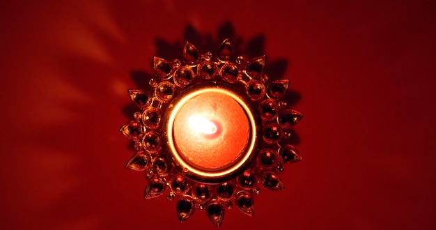 Photo bougie allumée dans la base ornementée du chandelier sur fond rouge foncé avec une ombre