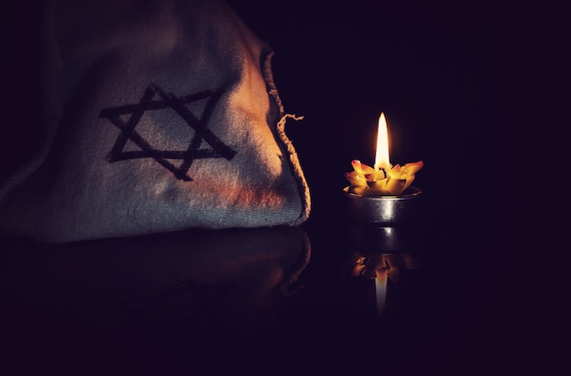 Bougie allumée et l'étoile de David sur fond noir Nous n'oublierons jamais le jour du souvenir de l'Holocauste juif et de l'héroïsme