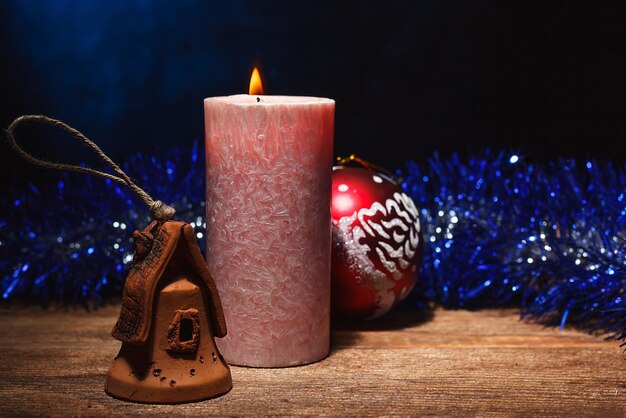 Une bougie allumée et des jouets de Noël avec des guirlandes se tiennent sur une surface en bois Préparation et réunion des vacances et des vacances de Noël