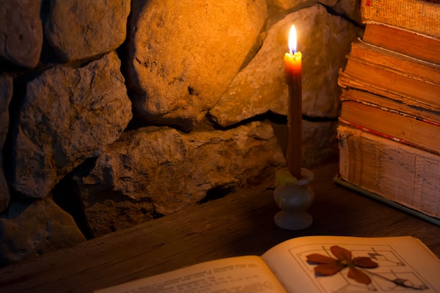 Bougie allumée sur la table et vieux livres