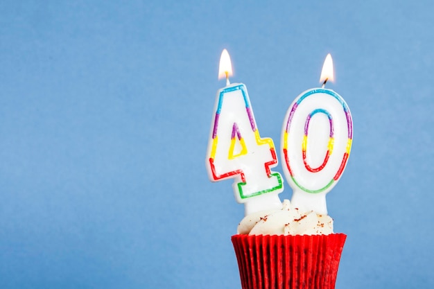 Bougie d'anniversaire numéro 40 dans un cupcake sur fond bleu