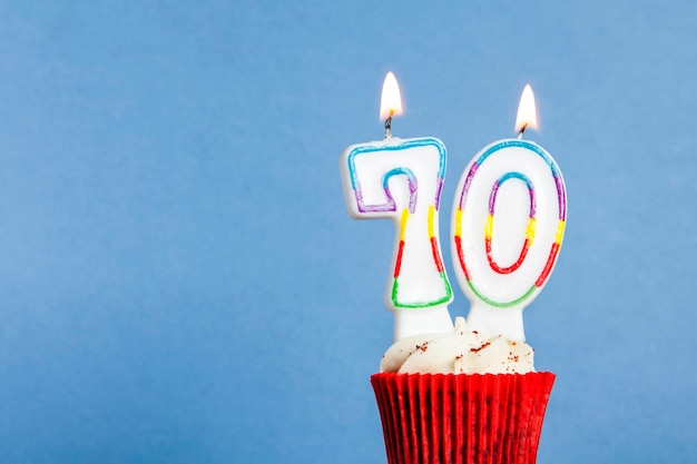 Photo bougie d'anniversaire numéro 70 dans un cupcake sur fond bleu