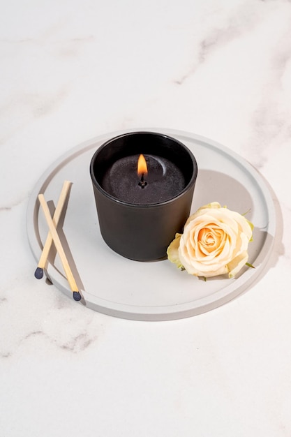 Bougie aromatique brûlante dans un bocal en verre dépoli noir à l'arôme d'épices Ambiance chaleureuse avec fleur de rose Style de vie confortable