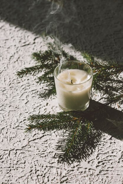 une bougie et une branche d'un sapin sur une maison confortable de fond clair