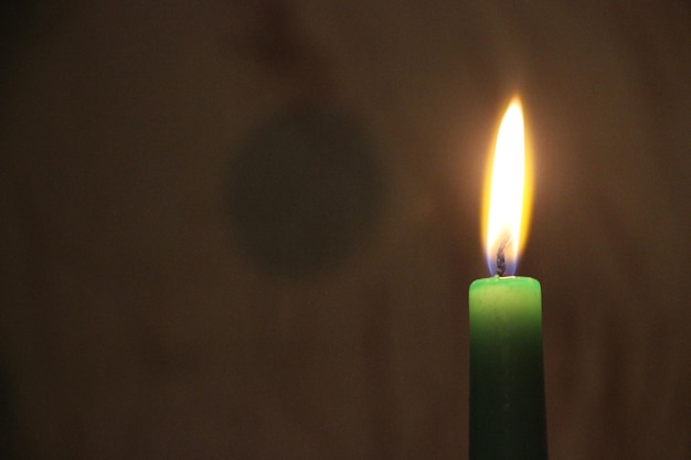 Bougie brûlante verte lumineuse dans l'obscurité