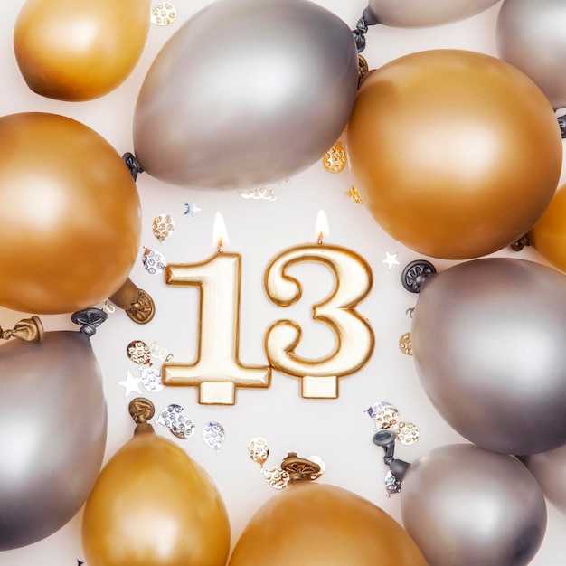 Photo bougie de célébration d'anniversaire numéro 13 avec des ballons d'or et d'argent