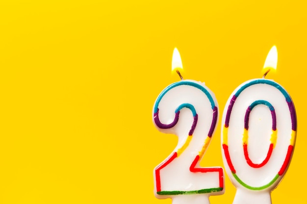 Bougie de célébration d'anniversaire numéro 20 sur un fond jaune vif