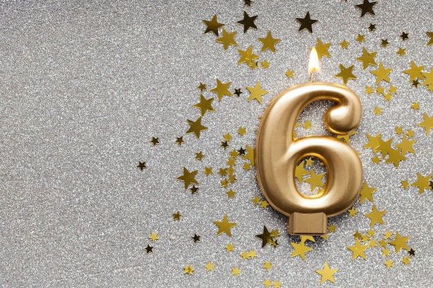 Bougie de célébration d'or numéro 6 sur fond d'étoile et de paillettes