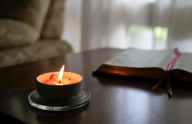 Bougie chauffe-plat brûlante sur table avec livre et canapé à l'arrière-plan