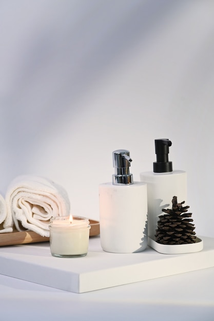 Bougie de cire brûlante, serviettes et bouteilles de savon sur fond blanc. Traitement de spa et concept de détente.