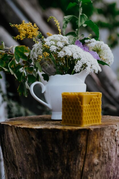 bougie en cire avec des fleurs rustiques sur table en bois