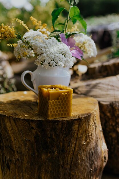 bougie en cire avec des fleurs rustiques sur table en bois