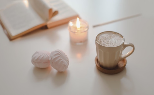 Bougie de fleur de tasse de café et un livre sur une vue de dessus de fond de table blanche