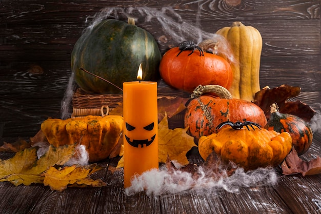 Une bougie d'halloween avec des citrouilles et des feuilles sur une table en bois.