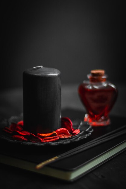 Bougie de livre en cuir noir potion rouge et bâtons rituels sur fond noir