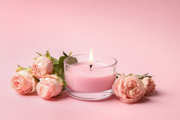 Bougie parfumée et roses sur surface rose