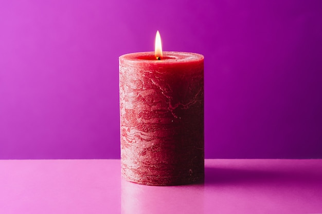 Bougie rouge brûlante sur surface violette