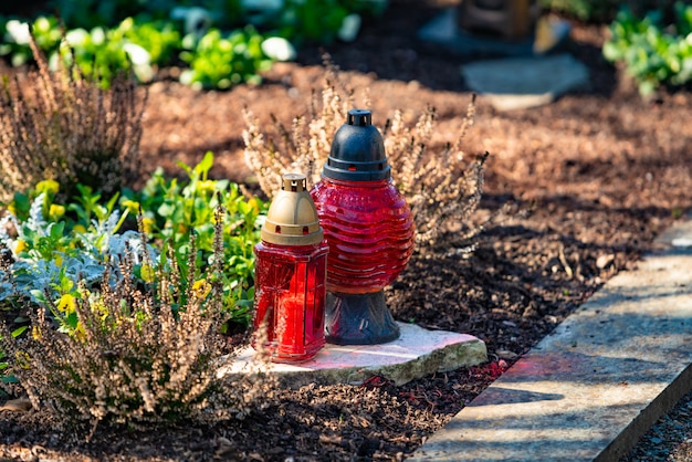 Une bougie rouge sur les pierres tombales avec des fleurs