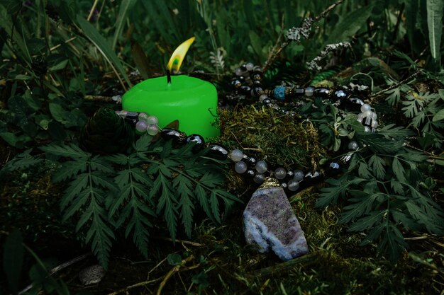 Bougie verte brûlante un symbole de la lune une amulette allongée sur une mousse sur un fond naturel sombre traditions slaves wiccan païennes sorcellerie rituel spirituel ésotérique