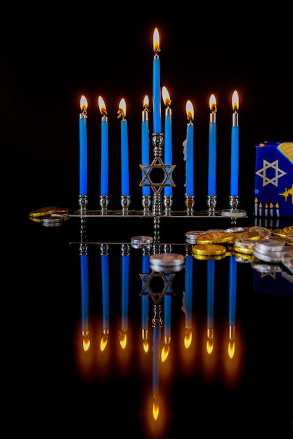 Bougies allumées bleues sur la menorah avec des pièces en chocolat pour la fête juive de Hanoukka.