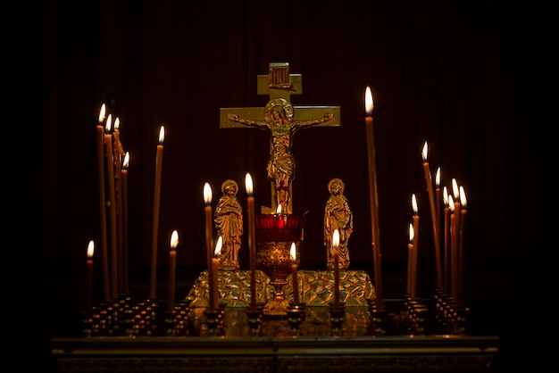 Bougies allumées avec une croix et un crucifix dans une église chrétienne dans le noir Gros plan Foi et religion