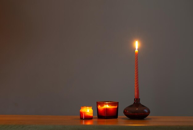 Bougies allumées dans des chandeliers en verre sur fond sombre