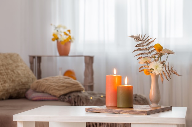 Bougies allumées avec décor d'automne sur table blanche à la maison