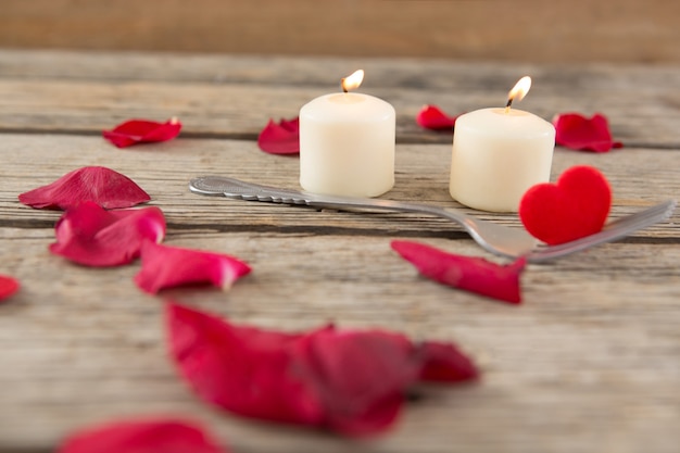 Photo bougies allumées entourées de pétales de rose aromatiques et d'une fourchette