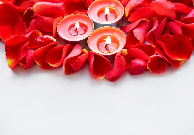Des bougies allumées entourées de pétales de rose