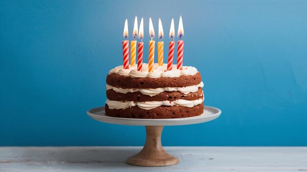 Des bougies allumées sur un gâteau d'anniversaire sur un stand de gâteau sur un fond bleu