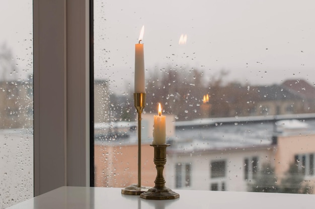 Bougies allumées sur la vitre de la fenêtre des pluies d'arrière-plan
