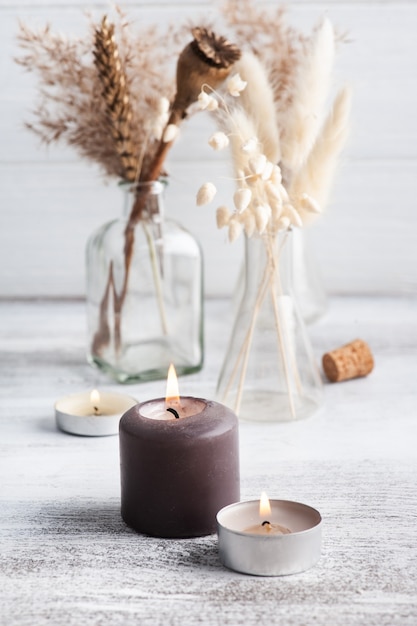 Bougies aromatiques allumées et fleurs sèches sur table rustique. Arrangement de spa dans un style monochrome