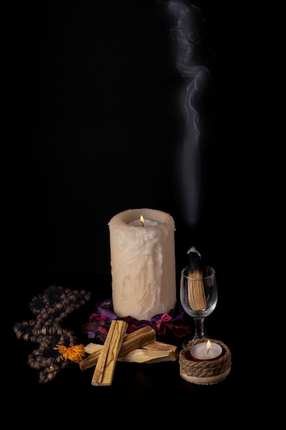 Photo des bougies, des bâtons d'encens et un verre d'eau sur la table.