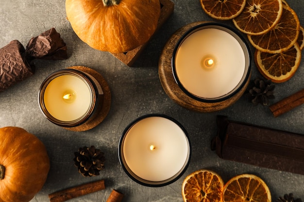 Bougies cannelle citrouilles et orange sur fond gris vue de dessus