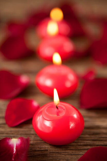 Bougies en cire rouge entourées de pétales de rose