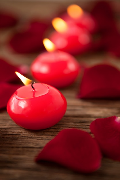 Bougies en cire rouge entourées de pétales de rose