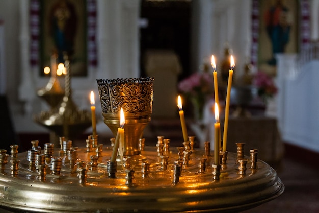 Les bougies de l'église brûlent dans un chandelier sur fond d'icônes