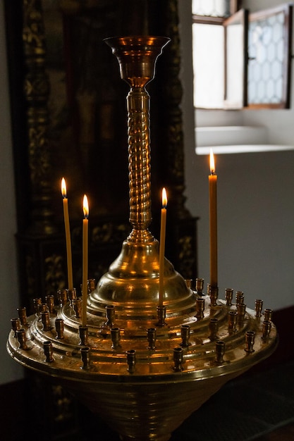 Les bougies de l'église brûlent dans un chandelier sur fond d'icônes