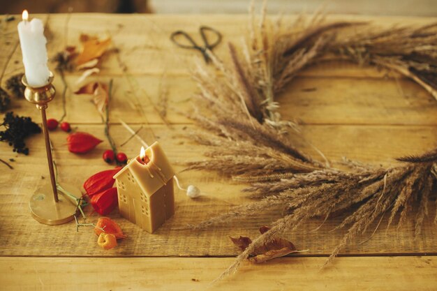 Photo bougies élégantes sur fond guirlande d'automne avec herbes séchées baies herbes sur table en bois