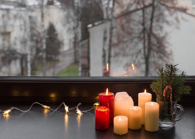 Des bougies de Noël sont allumées debout sur le rebord de la fenêtre