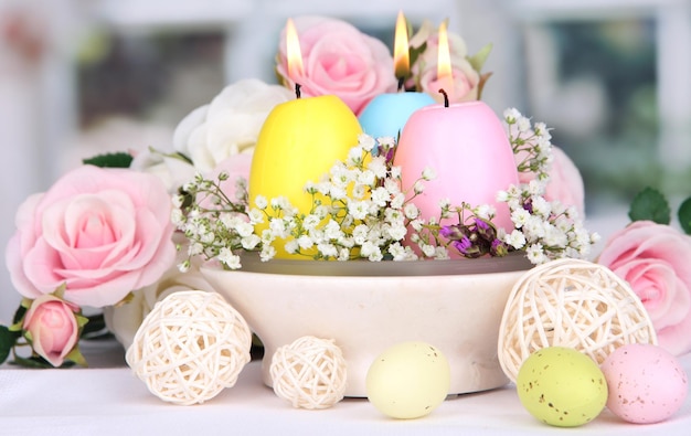 Bougies de Pâques avec des fleurs sur fond de fenêtre