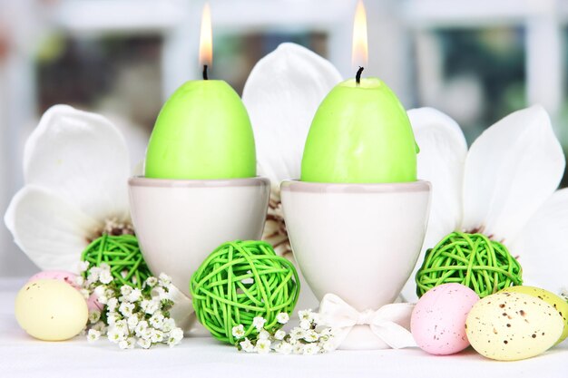 Photo bougies de pâques avec des fleurs sur fond de fenêtre