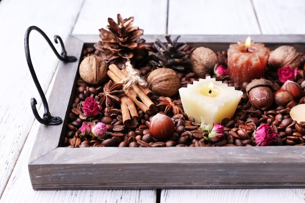 Bougies sur plateau vintage avec grains de café et épices, bosses sur fond de bois de couleur