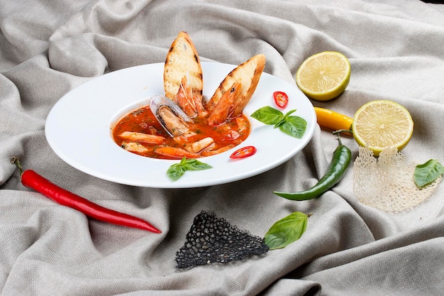 Bouillabaisse française soupe de poisson aux crevettes moules et pétoncles dans une assiette blanche sur un fond textile