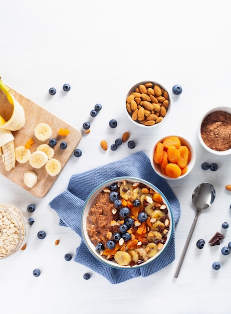 Bouillie d'avoine au chocolat avec myrtille, noix, banane, abricot sec pour un petit déjeuner sain. Vue de dessus