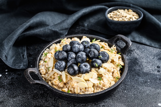 Bouillie d'avoine aux myrtilles et aux amandes. Fond noir. Vue de dessus.