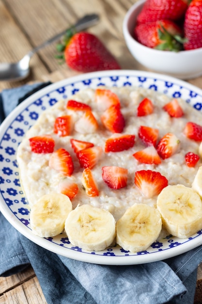 Bouillie d'avoine avec fraises et banane sur table rustique en bois