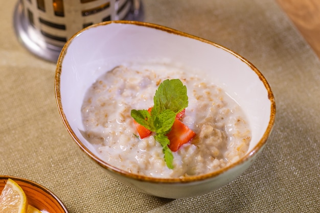 Bouillie d'avoine avec des tranches de pomme et de banane dans un bol blanc sur une table verte.