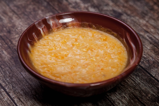 Bouillie de blé au lait d'amande sur fond de bois foncé. Santé des aliments traditionnels dans une assiette brune en forme de coeur avec de la bouillie de blé. Délicieux régime alimentaire sain. Espace de copie